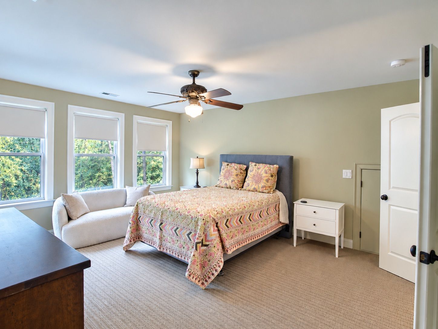 Bright bedroom with three windows and neutral decor