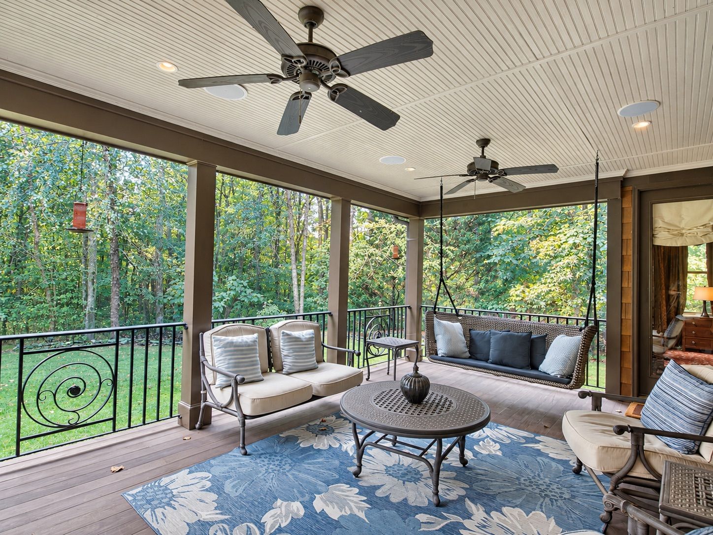 Covered back porch with ceiling fans, seating and wooded view