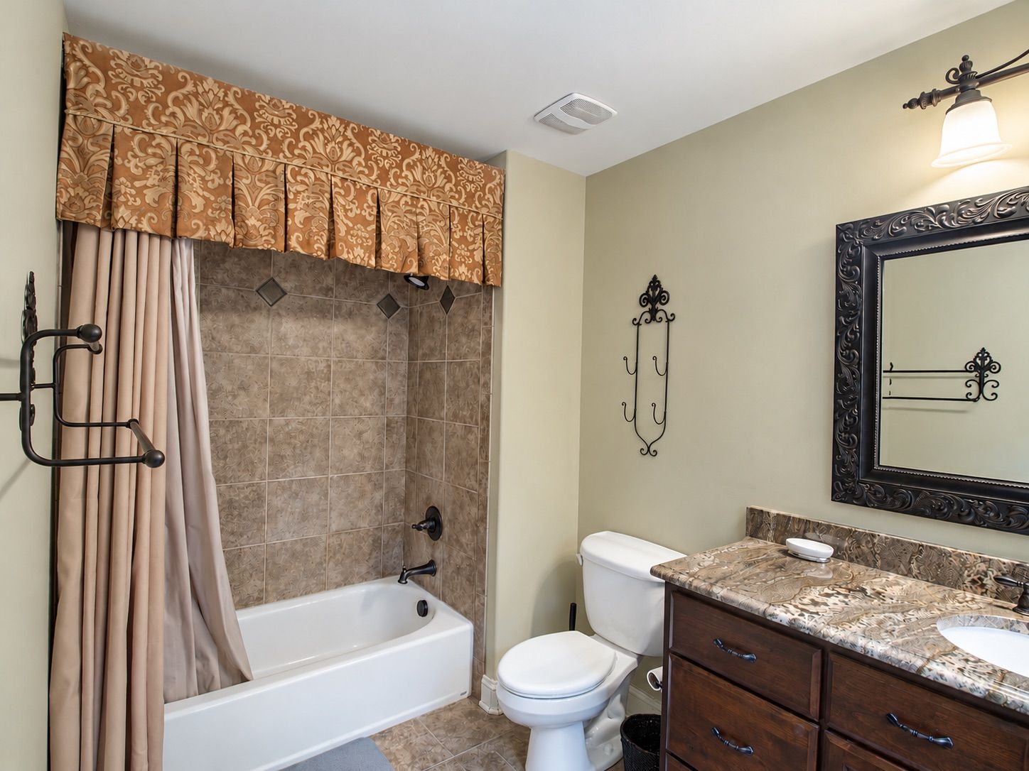 Hall bathroom with tiled tub surround and granite vanity