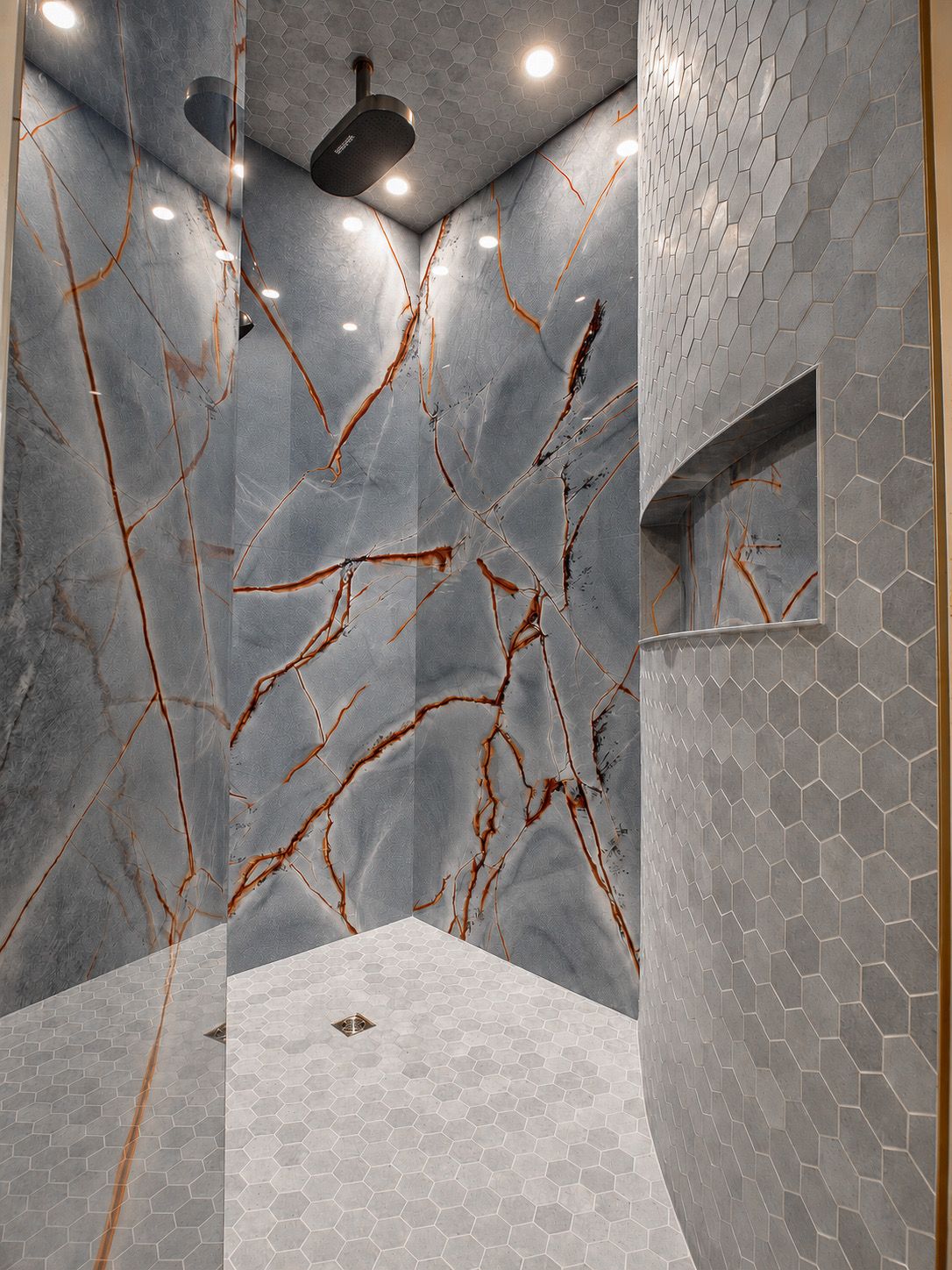Walk-in shower with veined stone walls and built-in niche